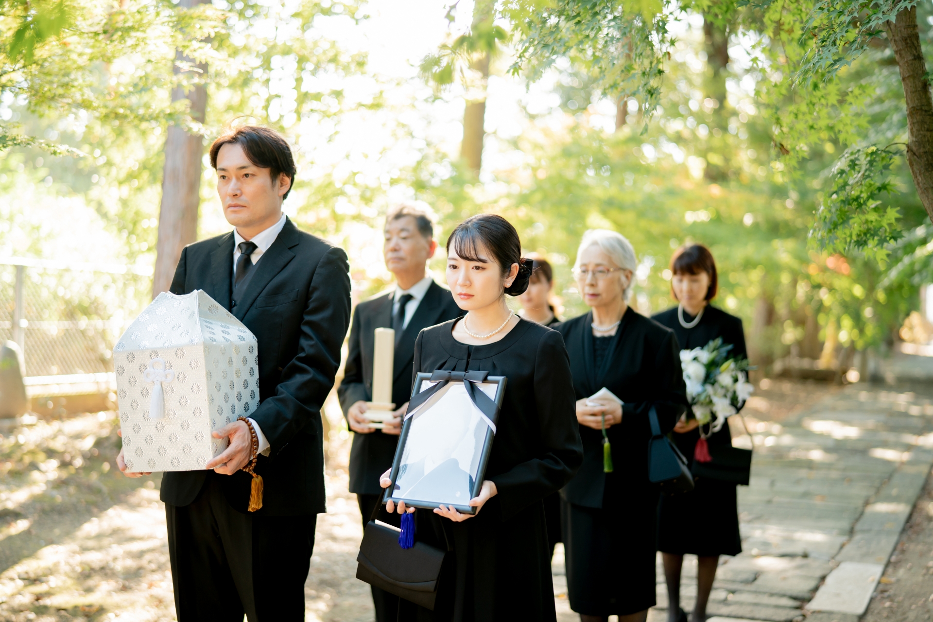 骨壷と遺影を持って歩いている写真